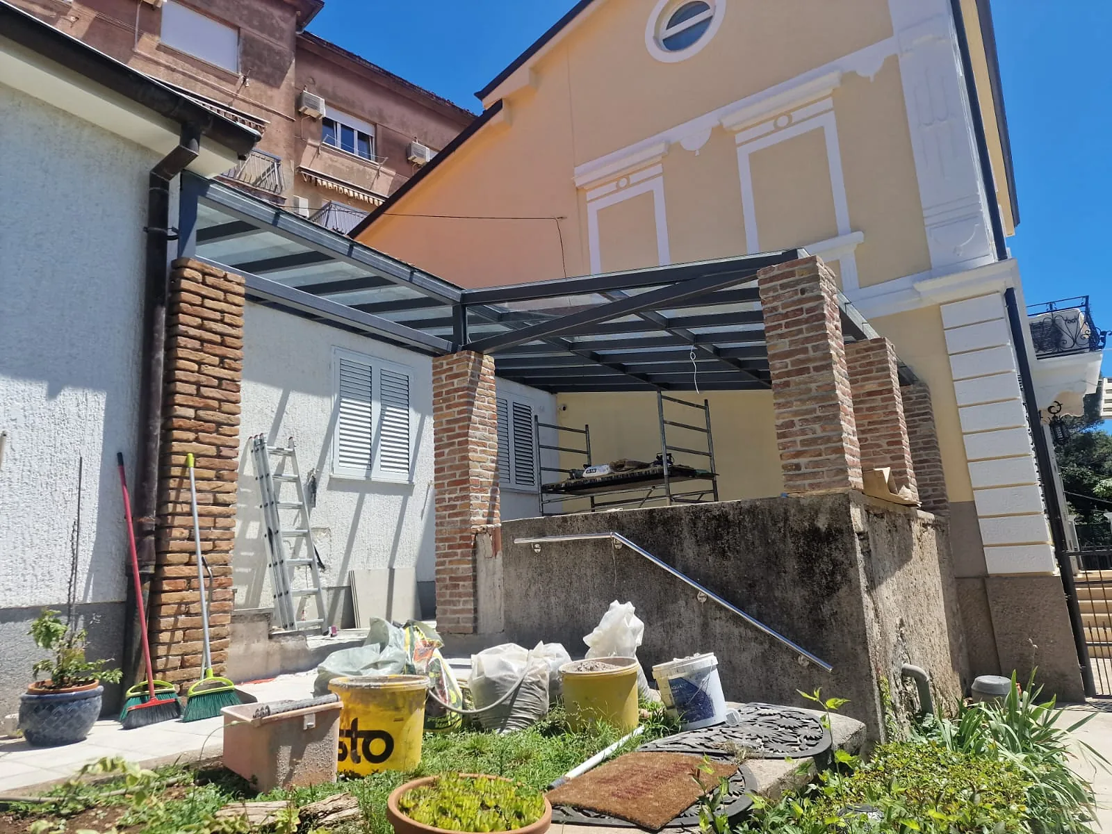 Stakleni krov pergole na čeličnoj konstrukciji između zidanih stupova